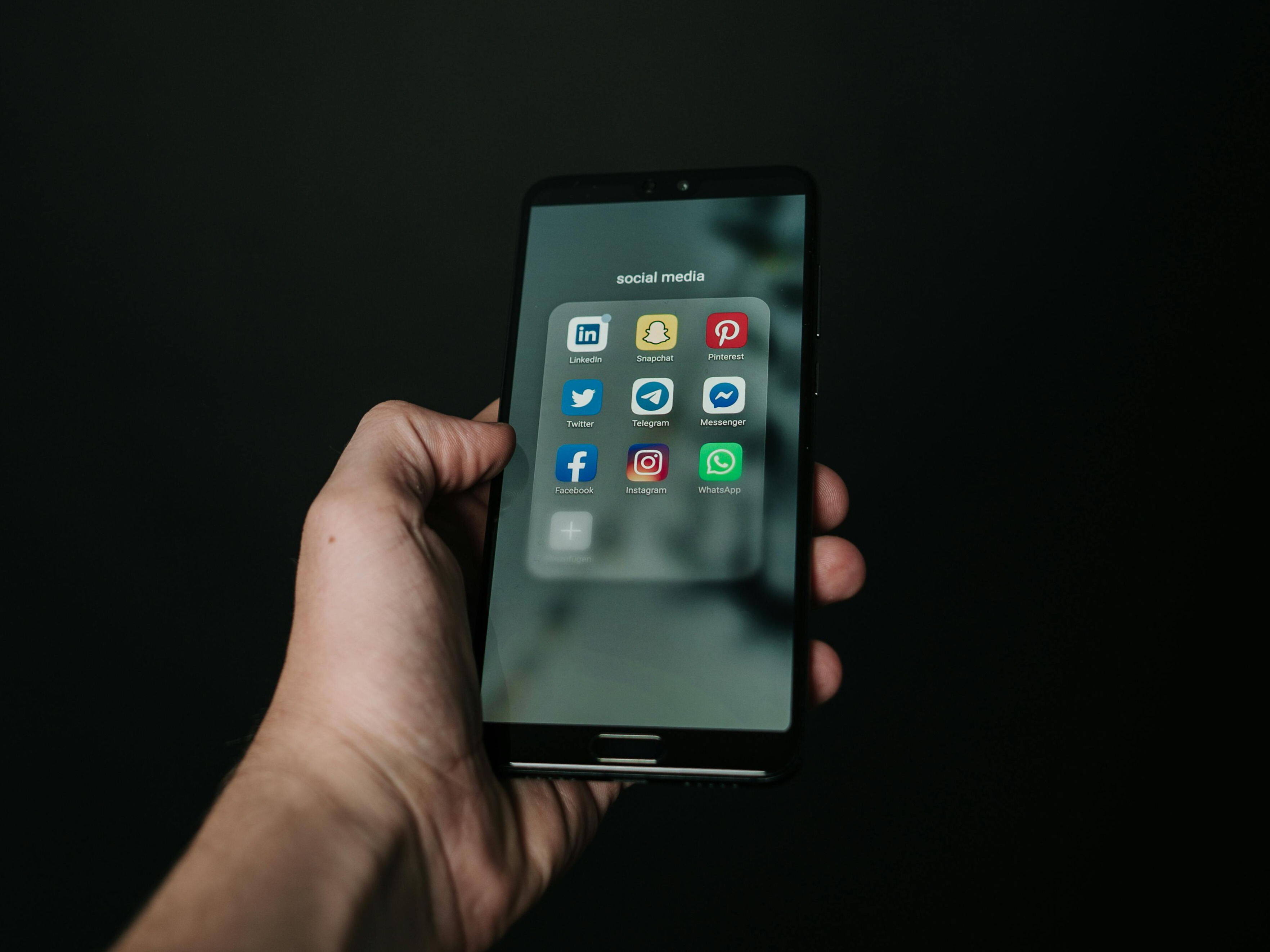 Hand holding phone open to multiple social media apps
