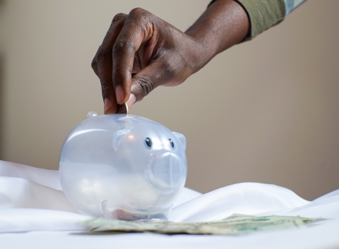 image of hand dropping coin in piggy bank