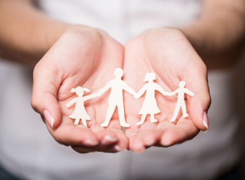 hands holding paper cutouts of a family