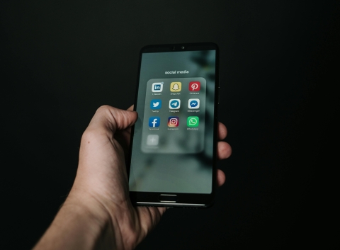 Hand holding phone open to multiple social media apps