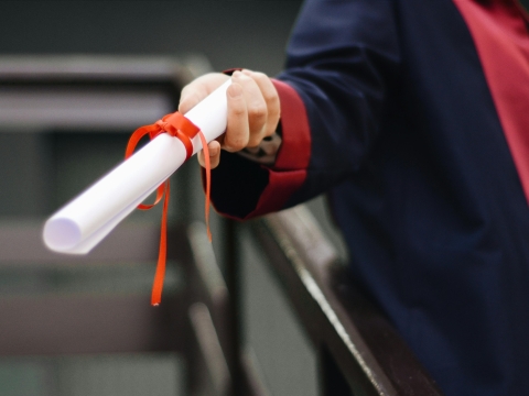 Person in graduation regalia holding diploma