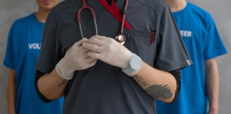 A doctor leading with volunteers in the background