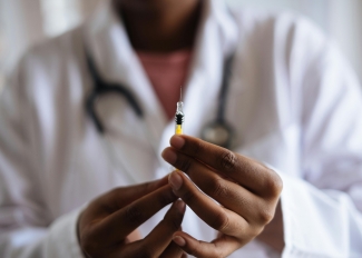 IMAGE OF A DOCTORE HOLDING VACCINATION SYRINGE