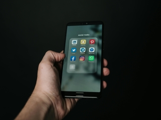 Hand holding phone open to multiple social media apps